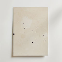 Postern Abstract Beige No.2 Poster by Bozetto har ett off-white premiumpapper med små, oregelbundna svarta bläckfläckar på den matta ytan, fotograferat mot en vit bakgrund.