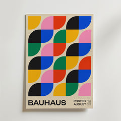 Bozetto Bauhaus Leaf Poster visar upp färgglad geometrisk konst i Bauhausstil med djärva gula, rosa, blå, gröna, röda och svarta former. Postern är perfekt för modern inredning och har texten "BAUHAUS" och "POSTER 19 AUGUST 23".
