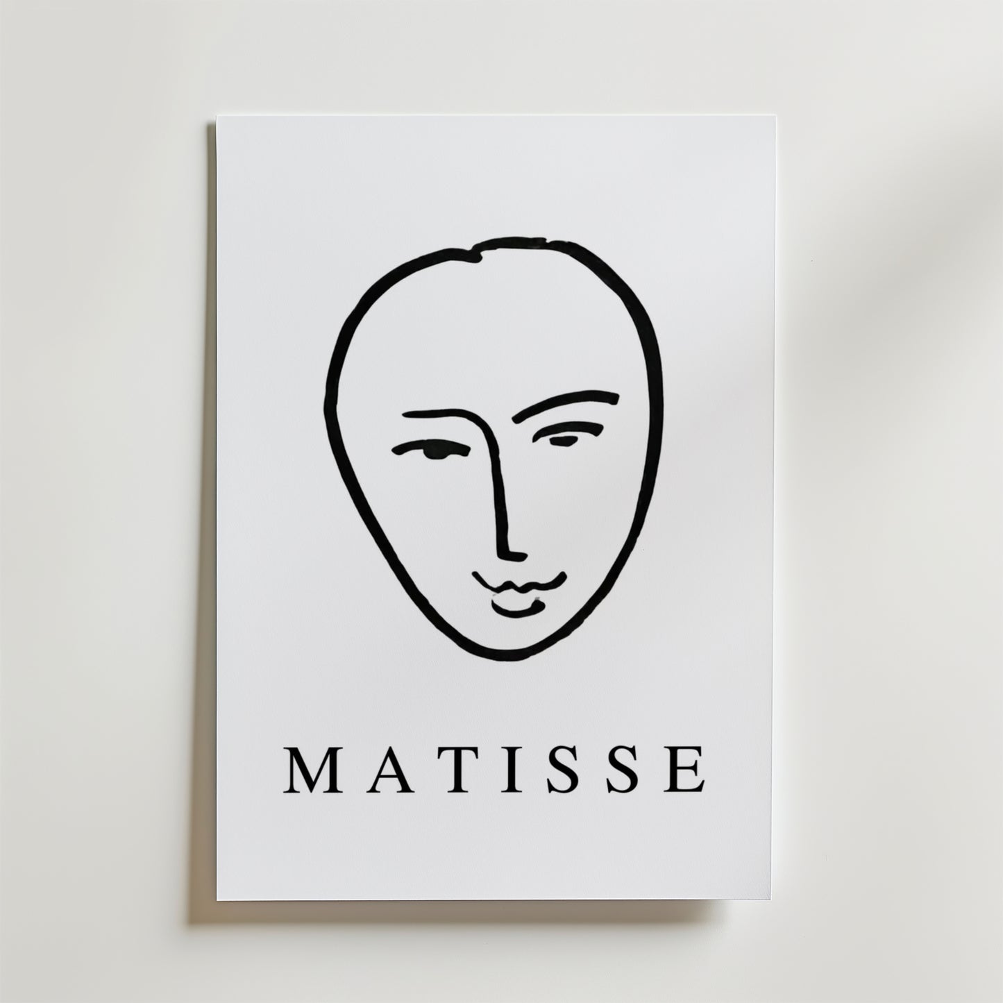 Minimal Matisse Poster by Bozetto har ett minimalistiskt svart linjeansikte på en vit bakgrund med fet "MATISSE" text, tryckt på premiumpapper med en matt finish för en elegant look.