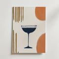 Bozettos Abstract Elegance Drink Poster visar ett mörkblått cocktailglas på en matt vit bakgrund, accentuerad av abstrakta vertikala linjer i guld och djärva orange halvcirklar, tryckt på premiumpapper.