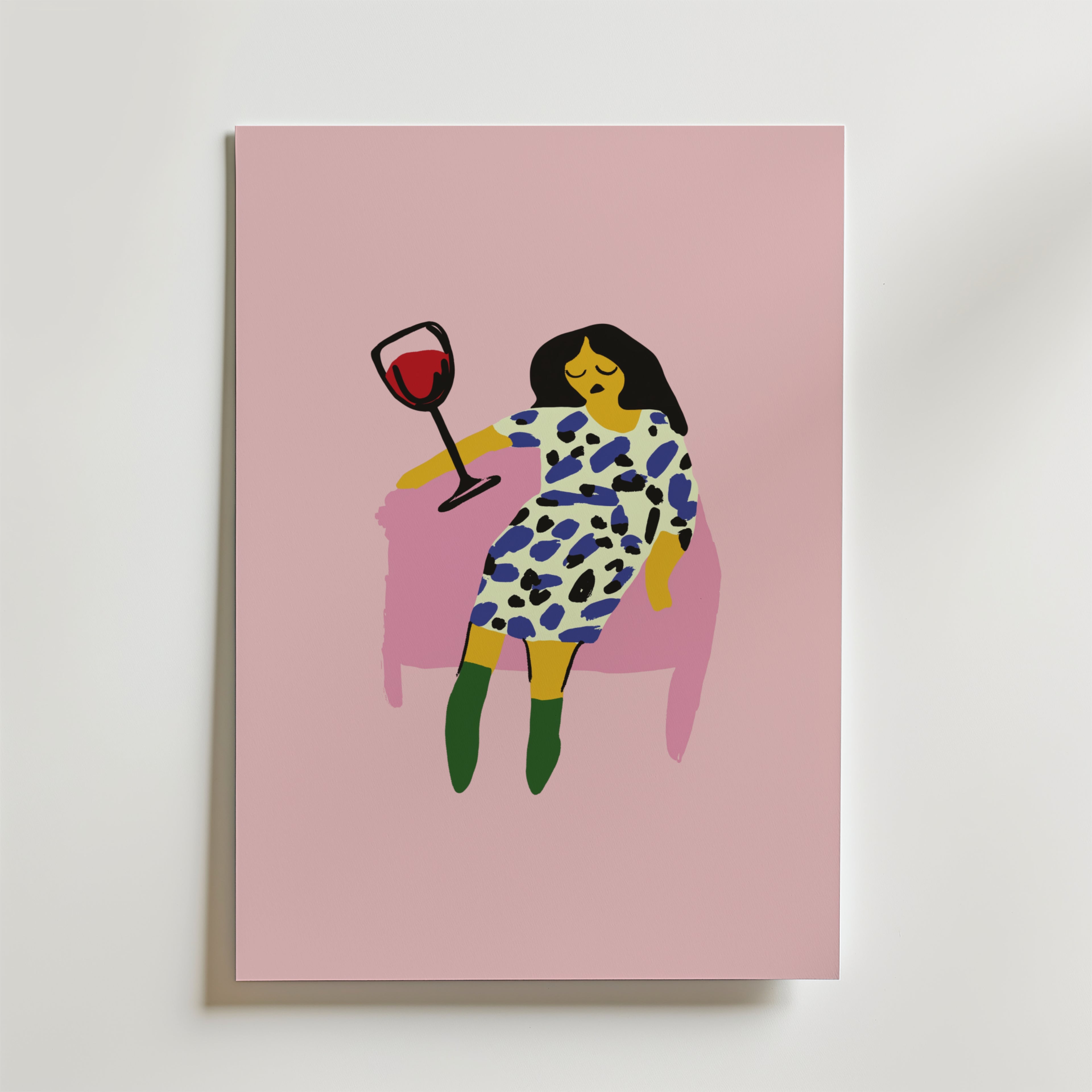 På postern Wine Down Poster från Bozetto syns en minimalistisk kvinna med mörkt hår i en mönstrad klänning och gröna boots, som slappnar av i en rosa stol med rödvin mot en rosa bakgrund. Tryckt på premiumpapper - perfekt för stilfulla inredningar.