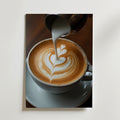En närbild av en vit kaffekopp med hjärtformad lattekonst medan mjölk hälls från en metallkanna - Bozetto's Elegant Barista Coffee Poster på premiumpapper med en lyxig matt finish för en raffinerad touch.