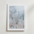 Frozen Branches Poster från Bozetto har skira frostvita växter på en mjuk, suddig bakgrund. Affischen är tryckt på FSC-certifierat premiumpapper med högkvalitativ finish och visas monterad på en ljus vägg.