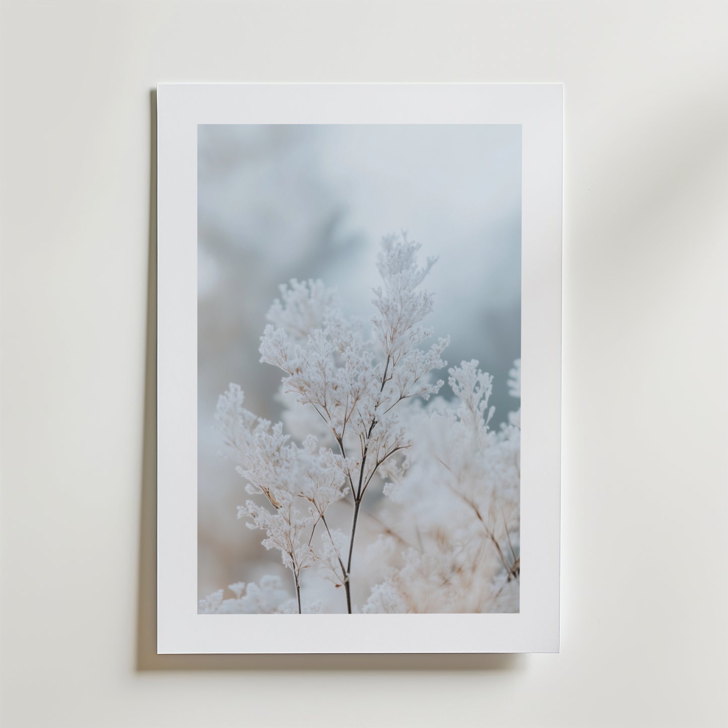 Frozen Branches Poster från Bozetto har skira frostvita växter på en mjuk, suddig bakgrund. Affischen är tryckt på FSC-certifierat premiumpapper med högkvalitativ finish och visas monterad på en ljus vägg.
