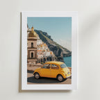 Bozetto Amalfi Coast Car Poster visar en gul veteranbil vid havet, färgglada byggnader och en kupol på klippiga klippor - allt för att fånga Medelhavets charm med en högkvalitativ finish.