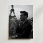 En man i kostym röker på en balkong med Eiffeltornet i bakgrunden. Bozetto Parisian Elegance Poster har en klassisk, stämningsfull stil - perfekt för att ge sofistikerad parisisk charm till alla rum.
