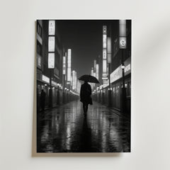 En ensam figur med ett paraply går på en våt stadsgata på natten, inramad av höga byggnader med glödande japanska skyltar, i denna stämningsfulla svartvita "Lonely Walk in the Rain Poster" från Bozetto.