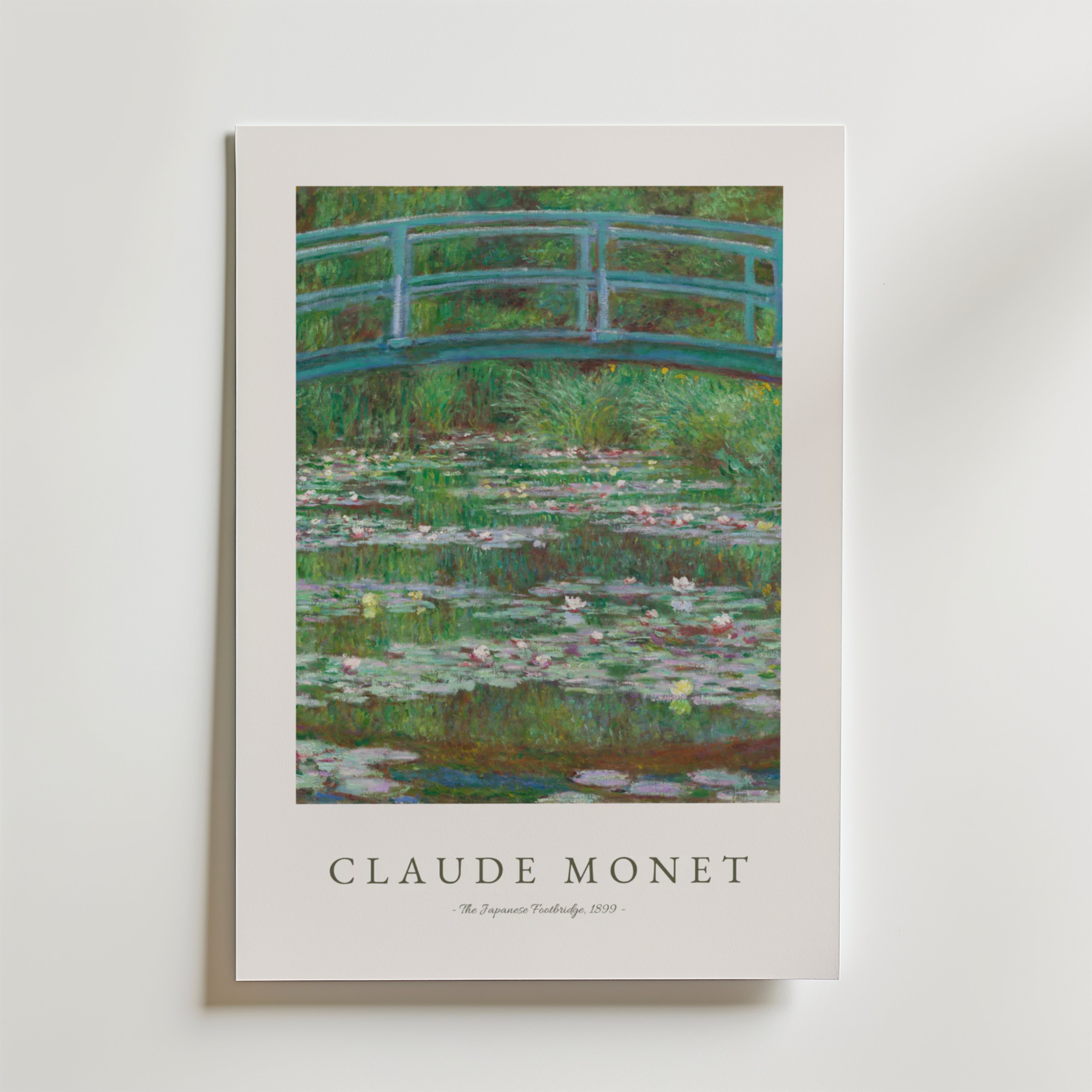 Bozetto Claude Monet Footbridge Poster visar The Japanese Footbridge med en grön bågbro över en damm med rosa näckrosor, frodig grönska och har Monets namn och konstverkets titel nedan på premiumpapper.