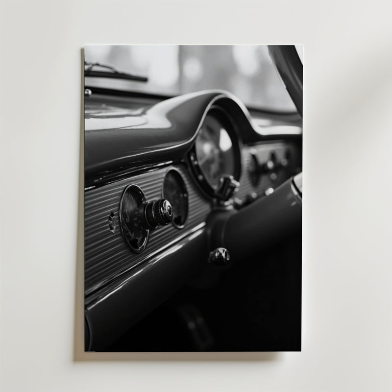 Bozetto's Old School Car Dashboard Poster visar ett svartvitt foto av en klassisk bils ratt, hastighetsmätare och vintagevred, tryckt på premiumpapper och uppsatt på en ljus vägg.