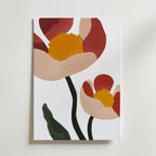 Bozetto Two Flowers Poster visar abstrakta blommor med röda kronblad, gul mitt och gröna stjälkar/blad mot en vit bakgrund, tryckt på FSC-certifierat premiumpapper för en modern look.