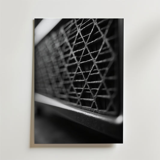 Bozetto's Vintage Speaker Poster visar en svartvit närbild av en geometrisk, diamantmönstrad metallgrill, fotograferad i vinkel mot en ljus bakgrund som framhäver de intrikata linjerna och formerna.