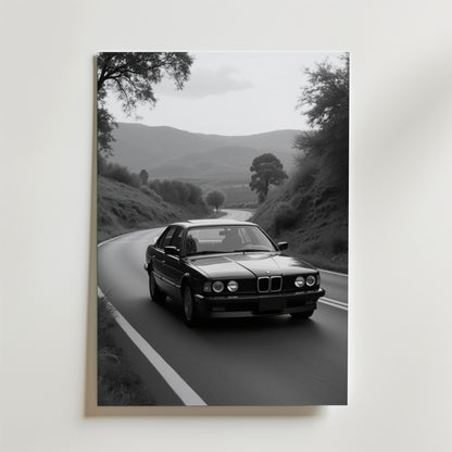 Vintage BMW Poster by Bozetto: Svartvitt foto av en klassisk sedan som kör på en slingrande väg genom kullar, omgiven av träd och berg, tryckt på premiumpapper med en lyxig matt finish.