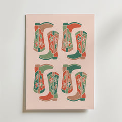 Boot Parade Poster by Bozetto har ett retro rutnätstryck av fyra par stiliserade cowboystövlar - sex stövlar - i grönt, rött och beige med enkla blommor på en ljusrosa bakgrund.