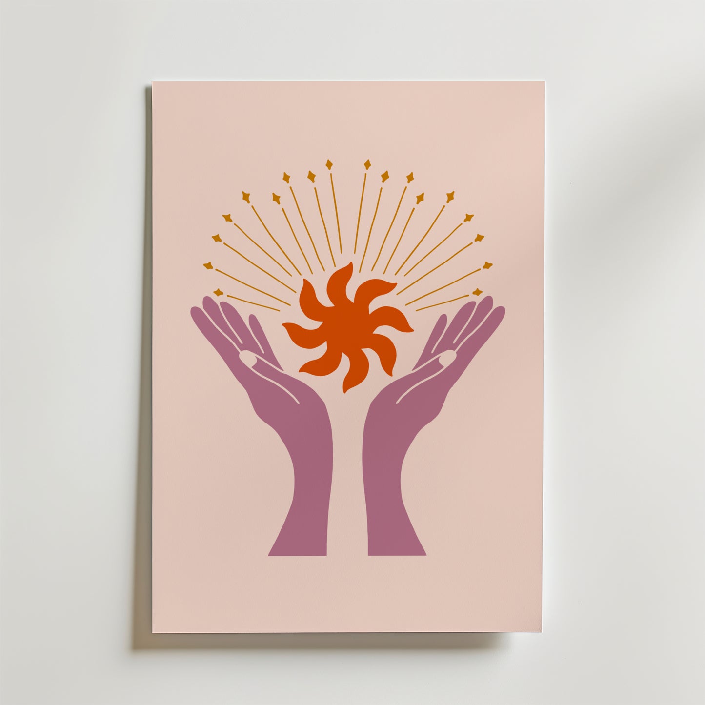 Bozetto Celestial Bloom Hands Poster har en minimalistisk illustration av två lila händer som håller en orange solstråle med guldstrålar mot en mjuk rosa bakgrund - en symbol för andlig energi.