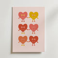 Colorful Heart Friends Poster från Bozetto föreställer sex glada hjärtfigurer i rosa, gult och rött med runda glasögon och leenden, som håller varandra i handen i tre rader mot en ljusrosa bakgrund - perfekt för barnrummet.