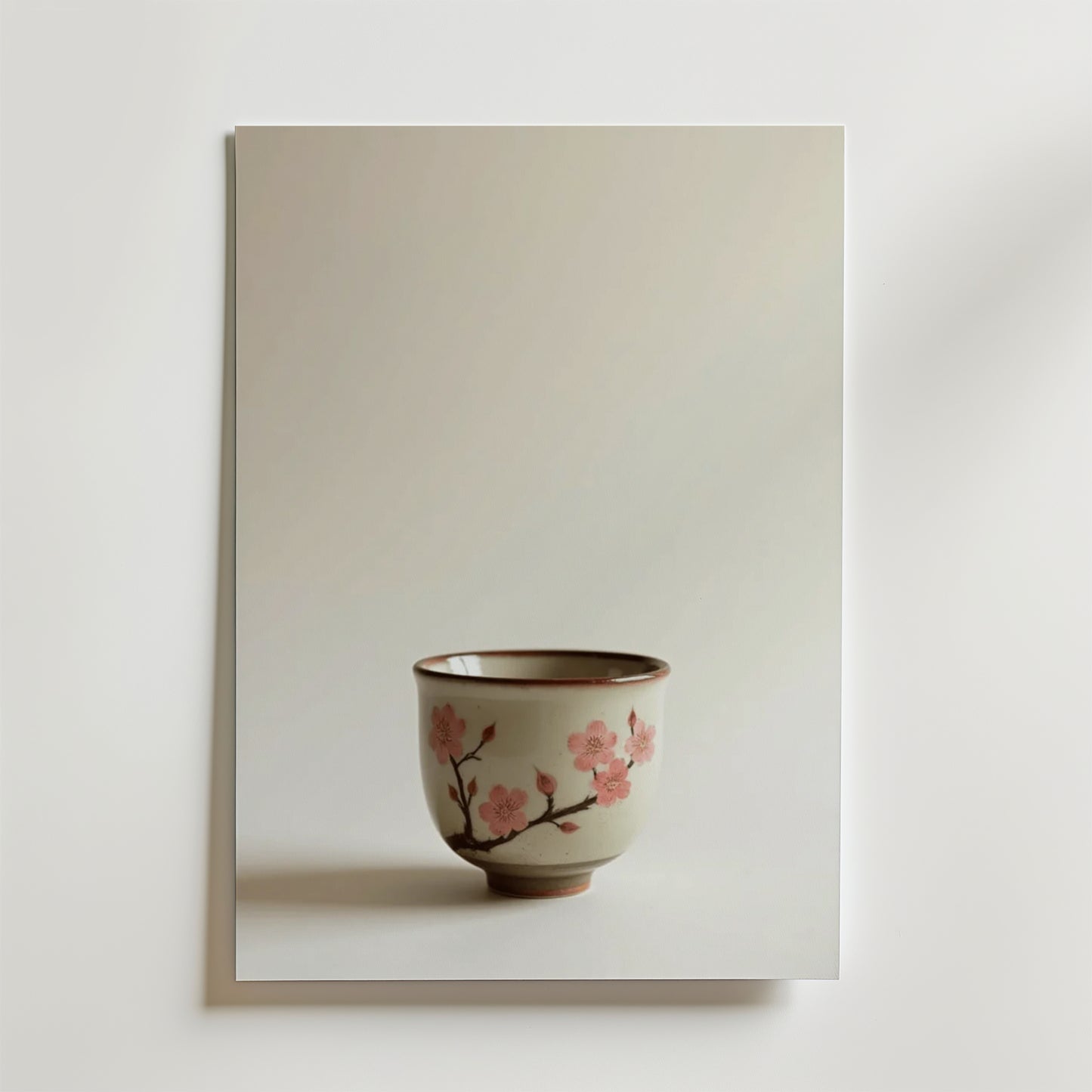 Bozetto Cherry Blossom Ceramic Cup Poster visar en keramikkopp med rosa körsbärsblommor och grenar mot en ljus bakgrund. Affischen är tryckt på premiumpapper och ger elegans och hållbar kvalitet till alla utrymmen.
