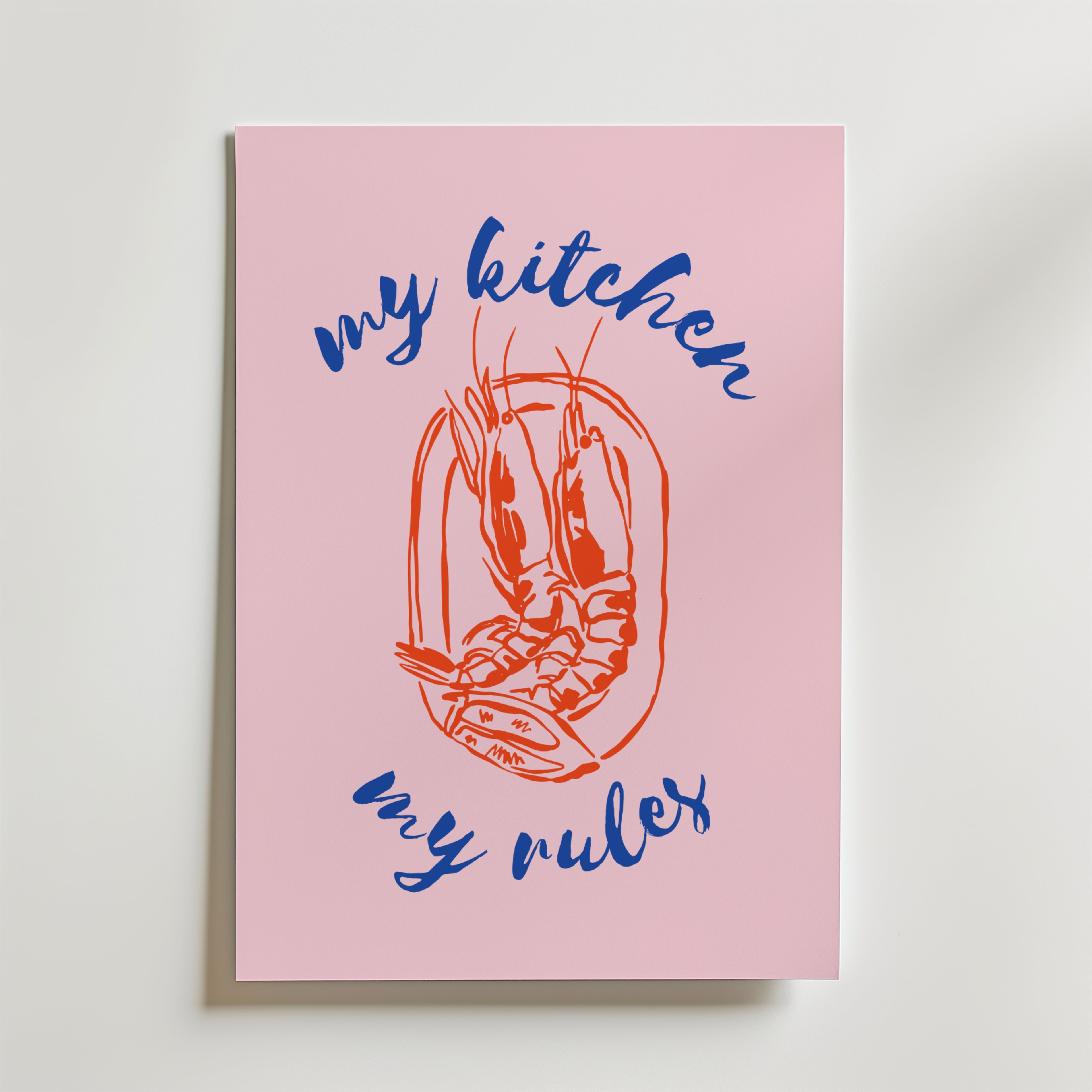 Bozetto My Kitchen My Rules Poster har en central röd räkillustration, omgiven av blå kursiv "my kitchen my rules" i rosa dekorstil, och är avbildad lutad mot en vit yta.