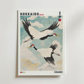 Bozetto Hokkaido Cranes Poster visar tranor i vintagestil som flyger mot en blå himmel med moln, en liten röd sol, japanska tecken och texten "Hokkaido Japan, Cranes" för en poetisk touch.