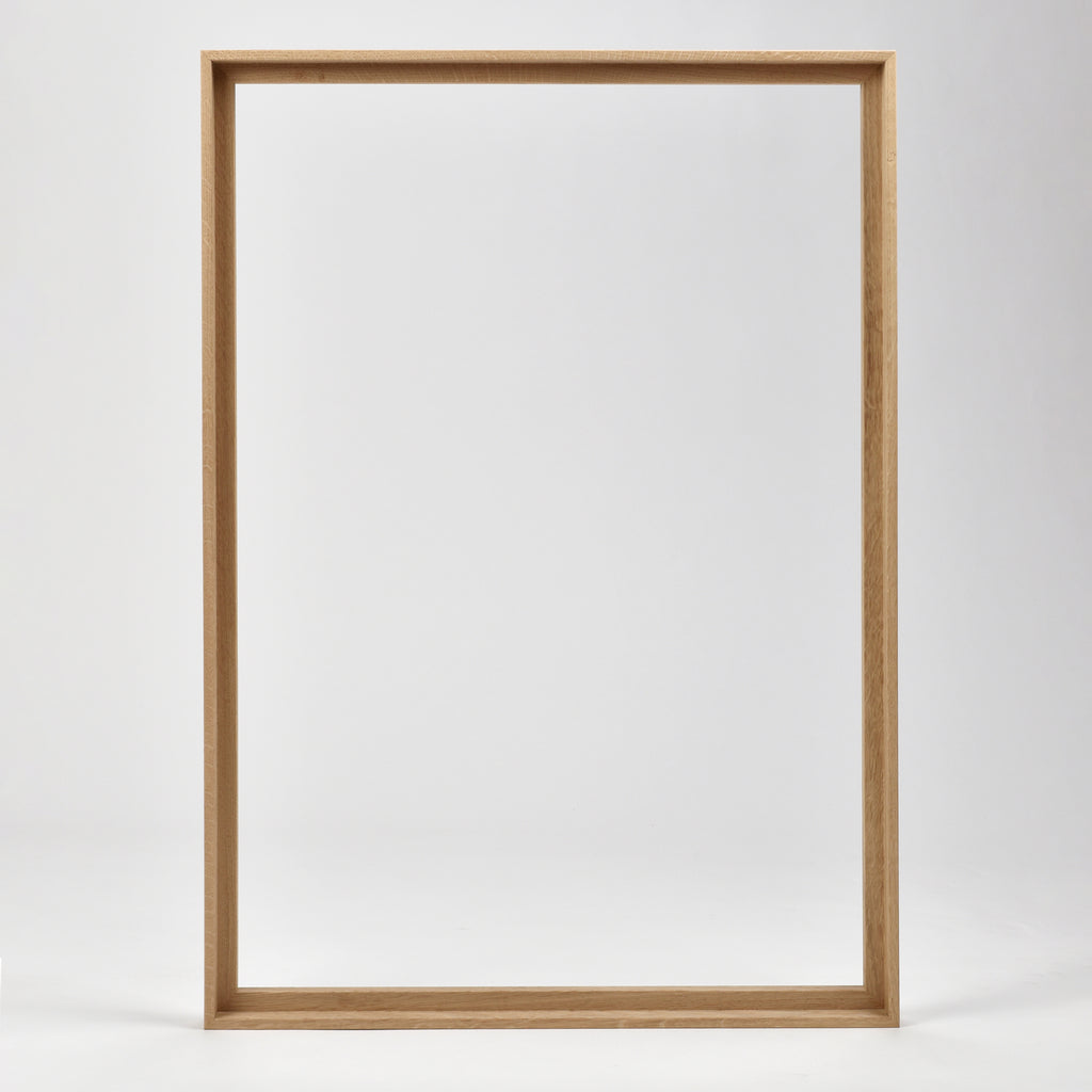 Bozetto Canvas Träram Ek är en enkel, tom tavelram i trä med en exklusiv träram, som står upprätt mot en vit bakgrund.