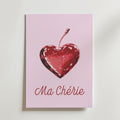 Ma Chérie Cherry Heart Poster från Bozetto har en romantisk design med en hjärtformad körsbärsillustration och "Ma Chérie" i elegant skrift på en ljusrosa bakgrund.