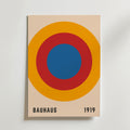 Bozetto Bauhaus Target Poster har koncentriska blå, röda och orange cirklar på beige med "BAUHAUS" och "1919" i svart - perfekt för dig som gillar grafisk design och vill ha en minimalistisk stil.