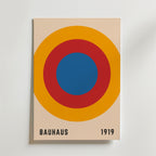 Bozetto Bauhaus Target Poster har koncentriska blå, röda och orange cirklar på beige med "BAUHAUS" och "1919" i svart - perfekt för dig som gillar grafisk design och vill ha en minimalistisk stil.