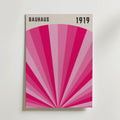 Bauhaus Pink Radiance Poster by Bozetto har "BAUHAUS" och "1919" högst upp, med geometriska rosa strålar som strålar ut från mitten på en ljus bakgrund, och kombinerar modern konst och klassisk design.