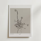 Floral Reverie Poster" från Bozetto föreställer minimalistiska blommor i en vas med svarta linjer på en neutral grå bakgrund, inramad av en vit kant. Denna eleganta poster tillför modern stil och raffinerad blomsterkonst till din inredning.