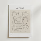 Postern Clay And Character Poster från Bozetto har minimalistiska svarta linjeteckningar av abstrakt keramik och vaser på en beige bakgrund, vilket ger kreativ inredning till alla rum. Postern visas uppställd mot en vit vägg.