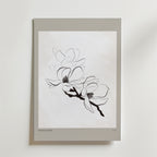 Soft Season Poster från Bozetto har en minimalistisk linjeteckning av två magnoliablommor på en gren och framhäver nordisk enkelhet med sitt vita papper, ljusgrå kant och rena vita bakgrund.